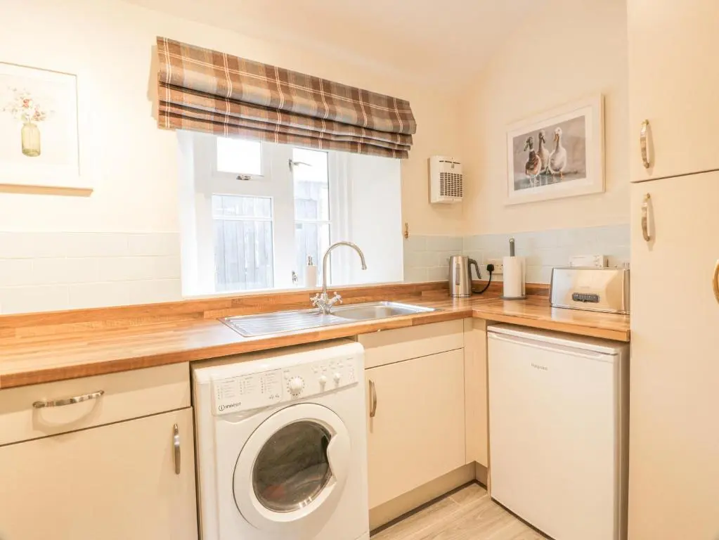 a kitchen with a washing machine and a sink at Beechgrove Cottage - Pitmedden Gardens in Ellon