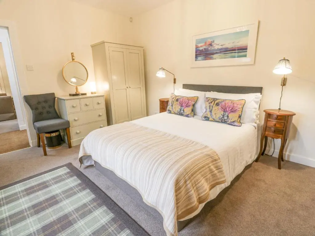 a bedroom with a large bed and a chair at Beechgrove Cottage - Pitmedden Gardens in Ellon