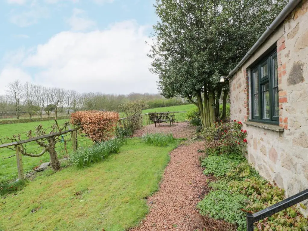 a garden with a table and a bench next to a building at Beechgrove Cottage - Pitmedden Gardens in Ellon