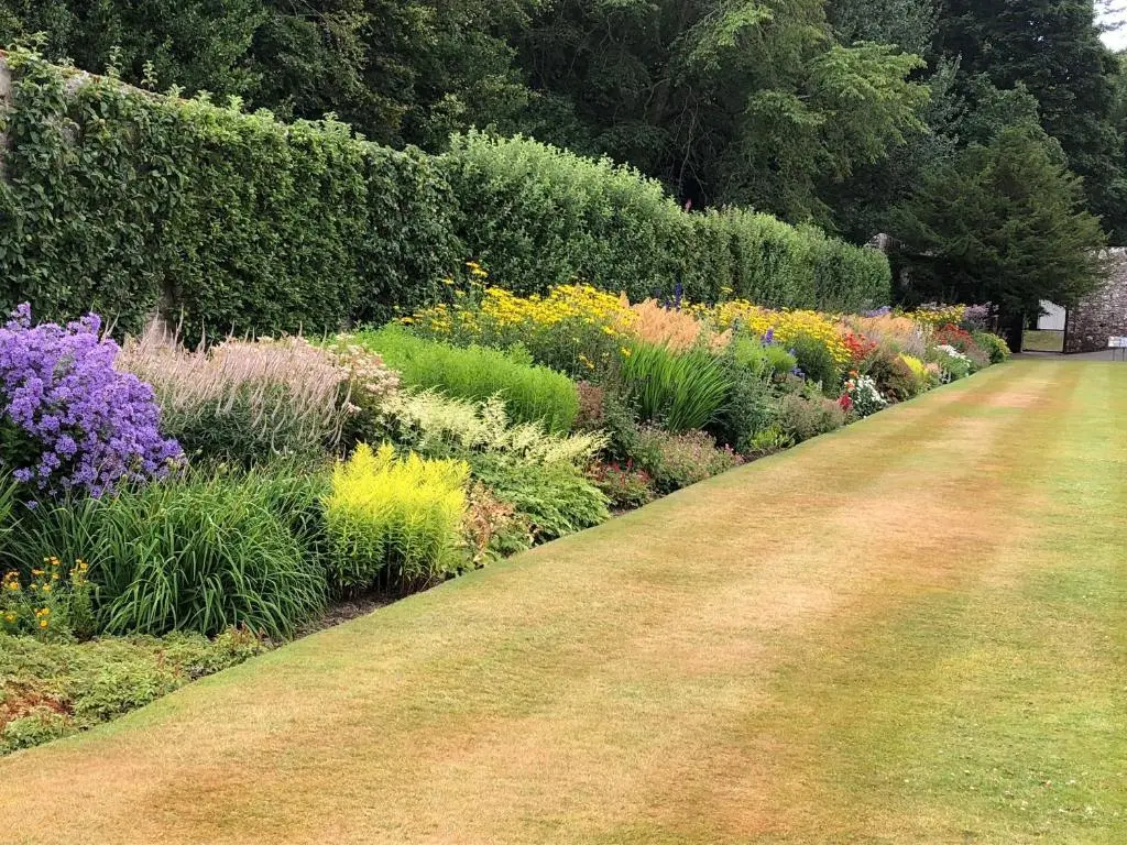a garden with colorful flowers and a dirt road at Beechgrove Cottage - Pitmedden Gardens in Ellon