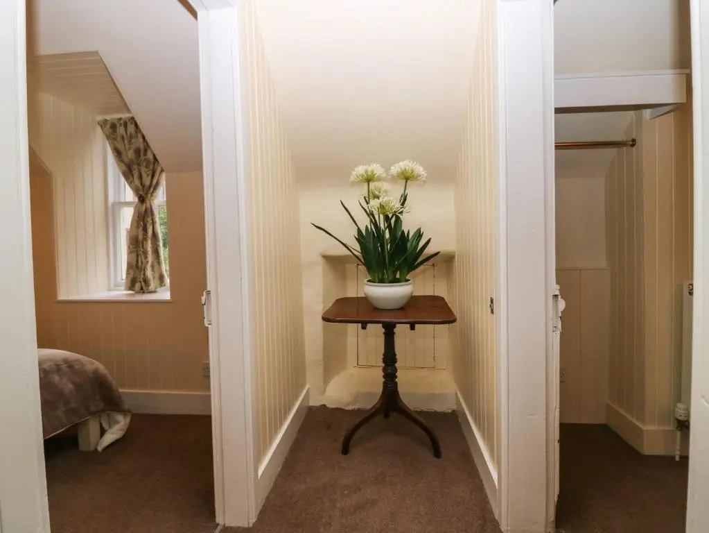 a hallway with a table with a vase of flowers on it at North Mains Cottage - Craigievar Castle in Alford