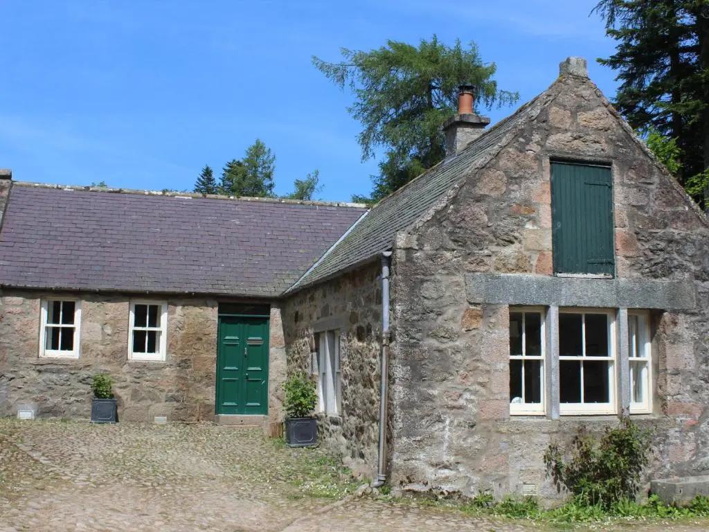 an old stone cottage with green doors and windows at Steading Cottage - Craigievar Castle in Alford