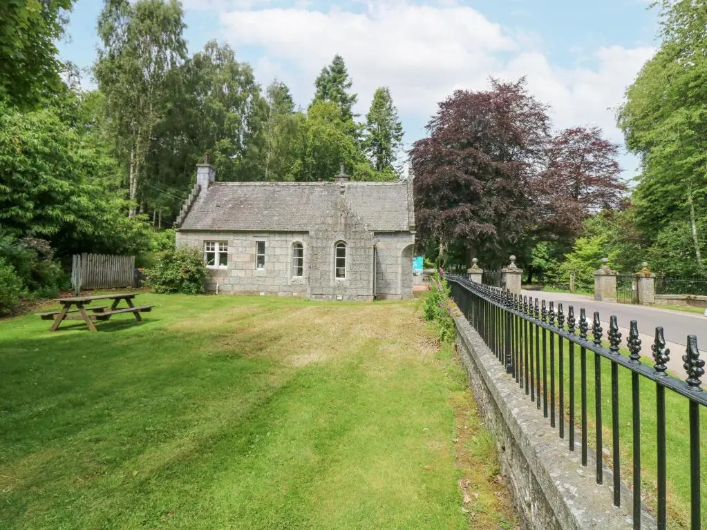 an old stone house with a picnic table and a fence at East Lodge - Crathes Castle in Banchory