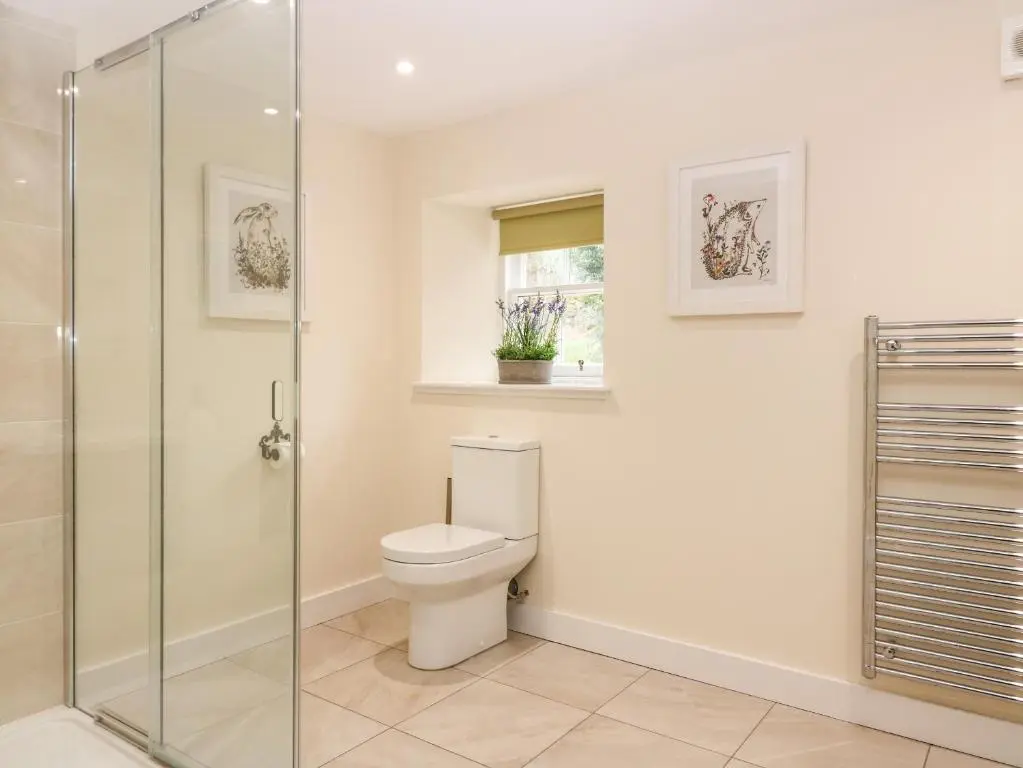 a bathroom with a toilet and a glass shower at South Mains Cottage - Craigievar Castle in Alford