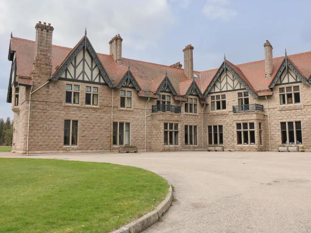 a large brick building with a grass field in front of it at Macdui - Mar Lodge Estate in Ballater
