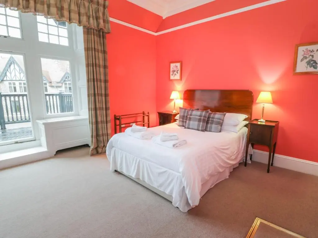 a bedroom with red walls and a bed with white sheets at Bynack - Mar Lodge Estate in Ballater