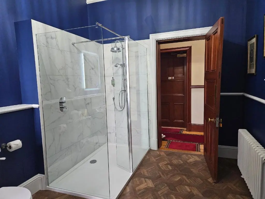 a glass shower in a bathroom with blue walls at Bynack - Mar Lodge Estate in Ballater