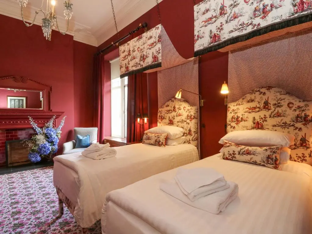 two beds in a room with red walls at Derry - Mar Lodge Estate in Ballater