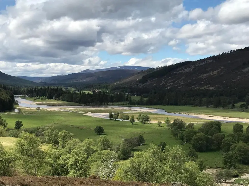 a view of a river in a field with trees at Derry - Mar Lodge Estate in Ballater