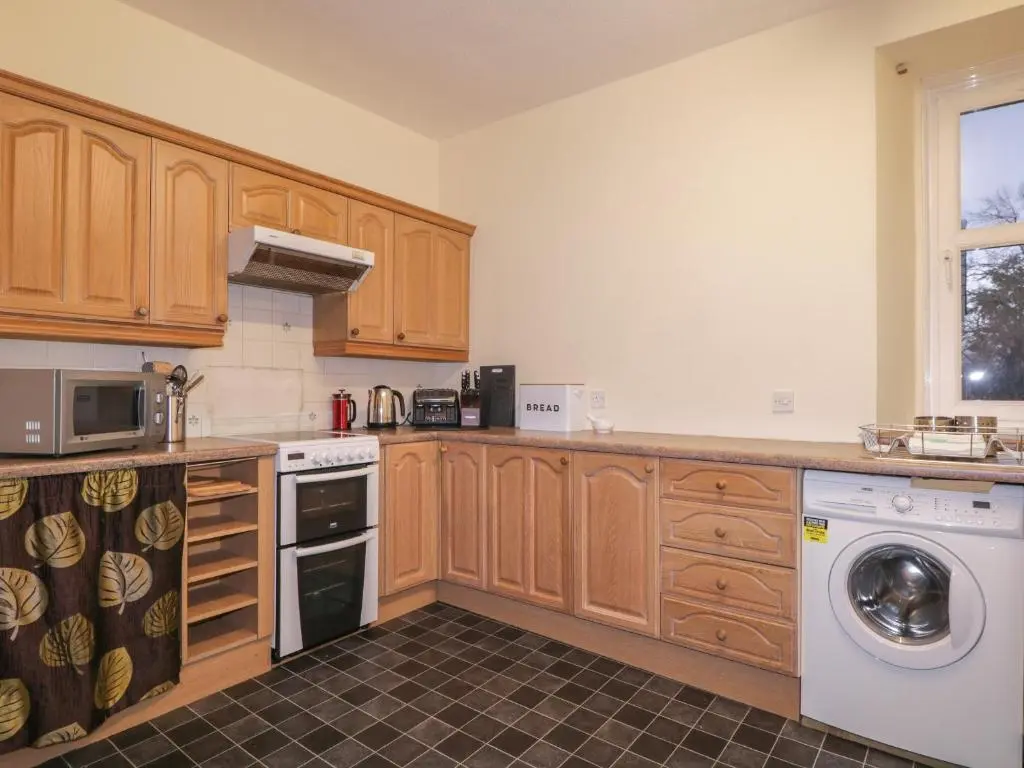 a kitchen with wooden cabinets and a washer and dryer at Kinnaird House in Grantown on Spey