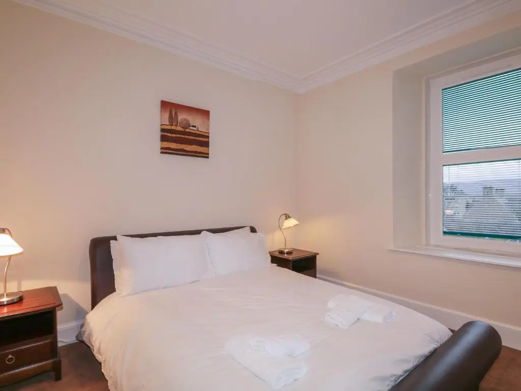 a bedroom with a bed with white sheets and a window at Kinnaird House in Grantown on Spey