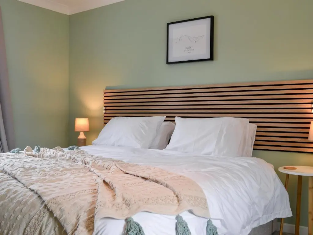 a bedroom with a large white bed with a wooden headboard at The Grain Store in Aberarder