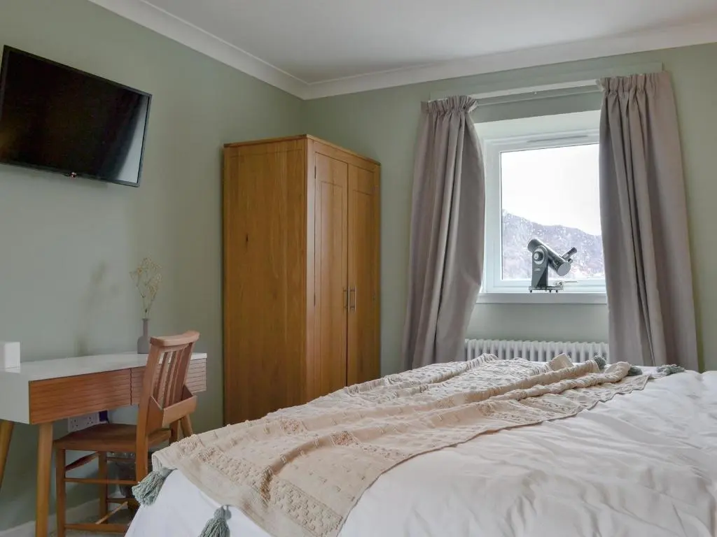 a bedroom with a bed and a desk and a window at The Grain Store in Aberarder