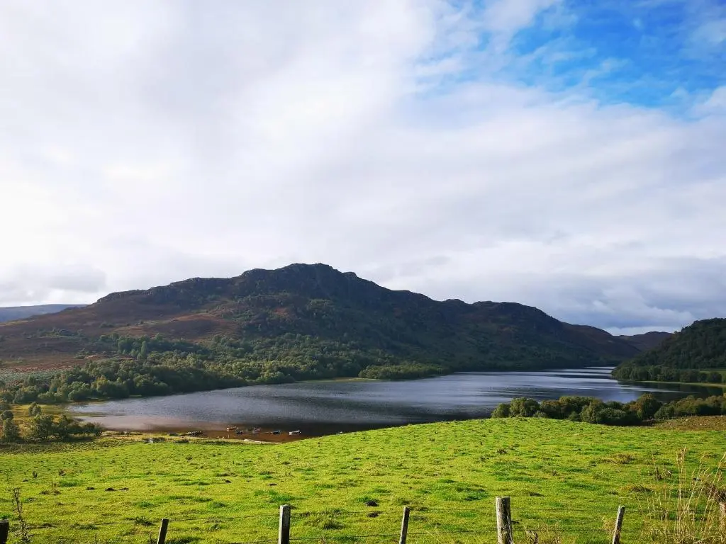 a lake in a field with a mountain in the background at The Grain Store in Aberarder
