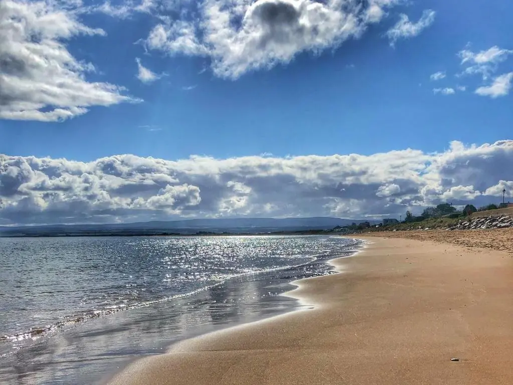 a beach with a cloudy sky and the water at Wester Links in Fortrose