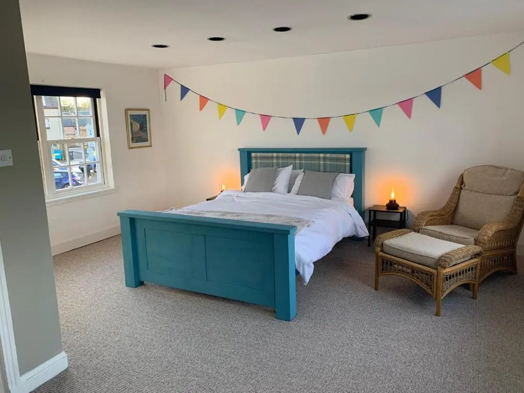 a bedroom with a blue bed and a chair and flags at Hill House - Mews Town House, in a quiet private close, in the City Centre of Inverness. in Inverness