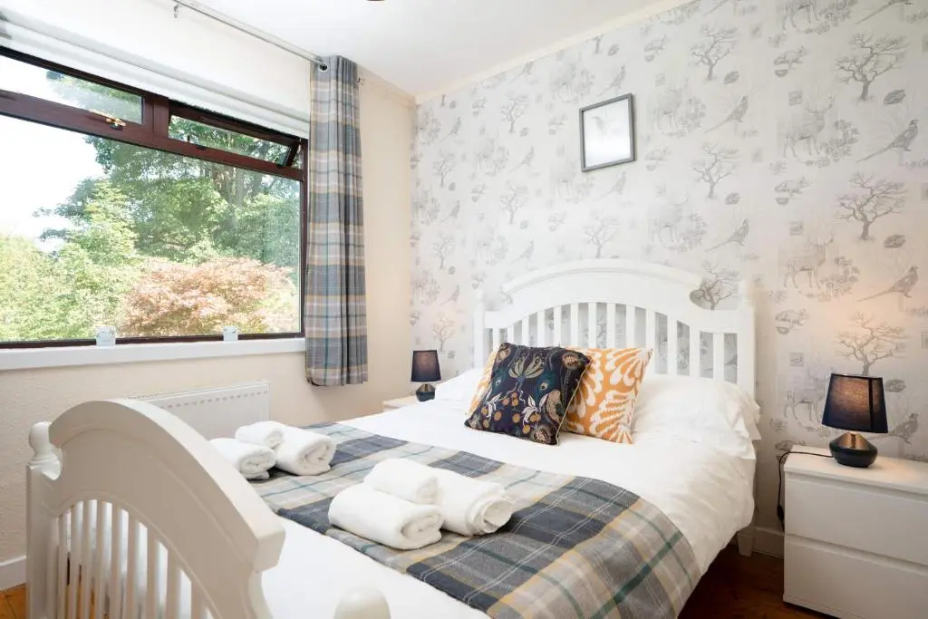 a bedroom with a white bed and a window at Kinloch Lodge in Bearnock