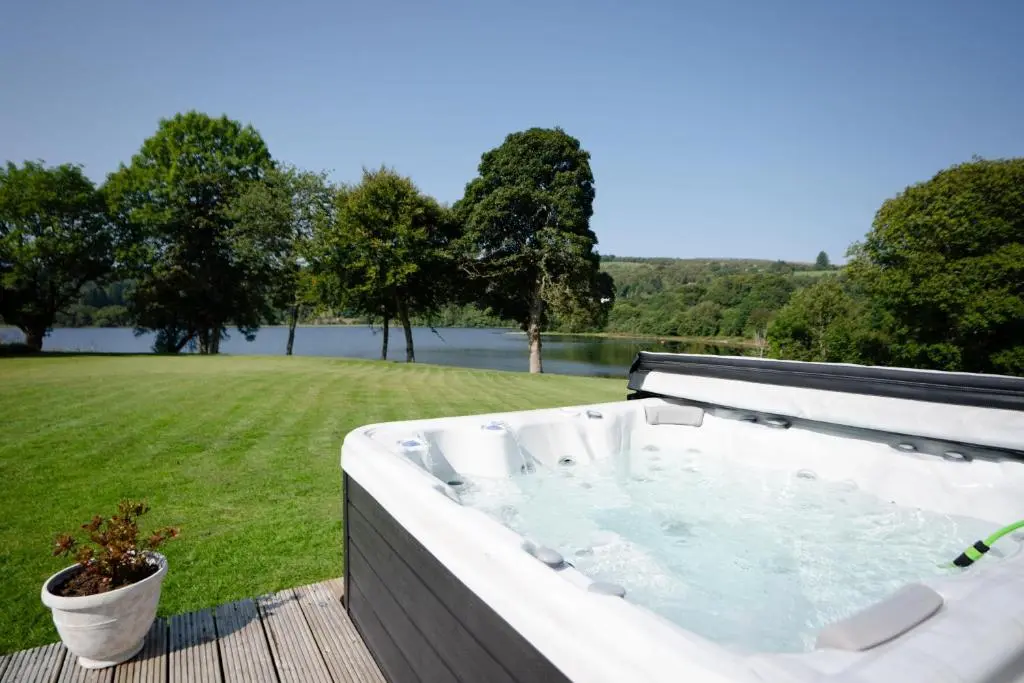 a hot tub on a deck with a view of a field at Kinloch Lodge in Bearnock