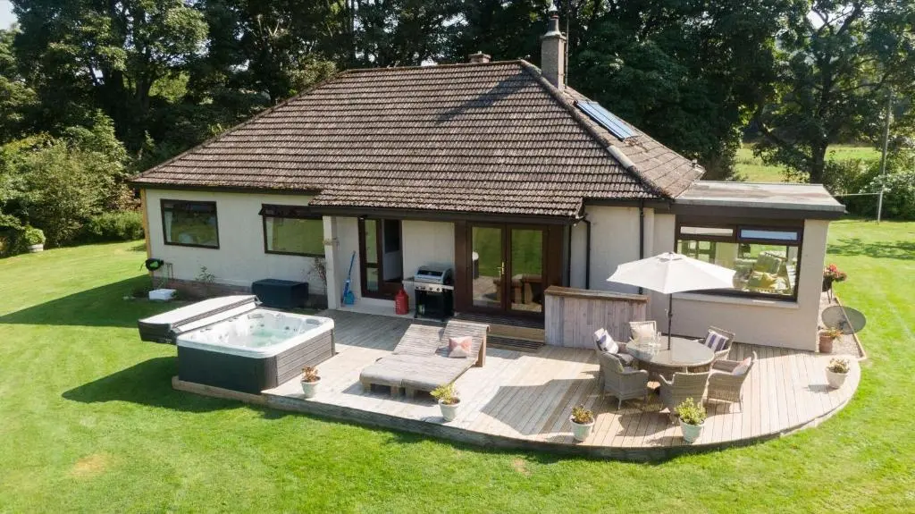 a small house with a deck with a hot tub at Kinloch Lodge in Bearnock