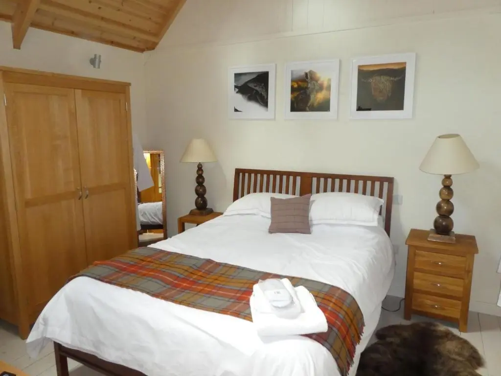 a bedroom with a large white bed with a dog laying on the floor at Wildcat Lodge in Boat of Garten