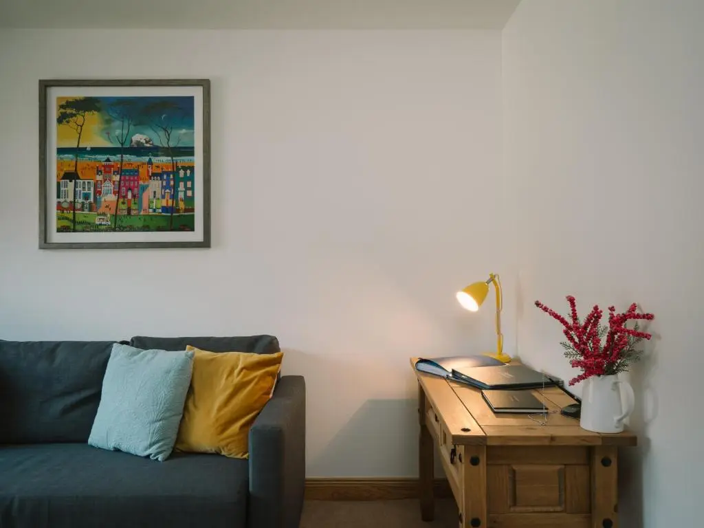 a living room with a couch and a table with a lamp at Snowmass Lodge - hot tub in Aviemore in Aviemore