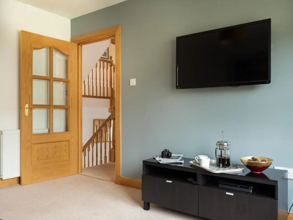 a living room with a flat screen tv on a wall at Snowmass Lodge - hot tub in Aviemore in Aviemore