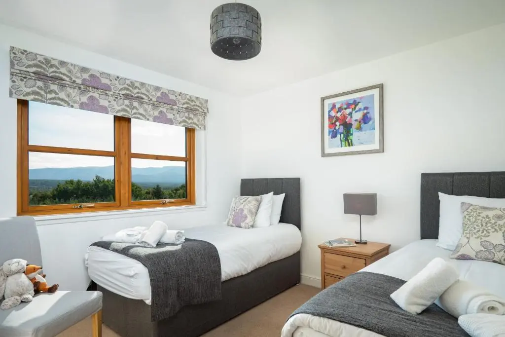 a bedroom with two beds and a window at Snowmass Lodge - hot tub in Aviemore in Aviemore