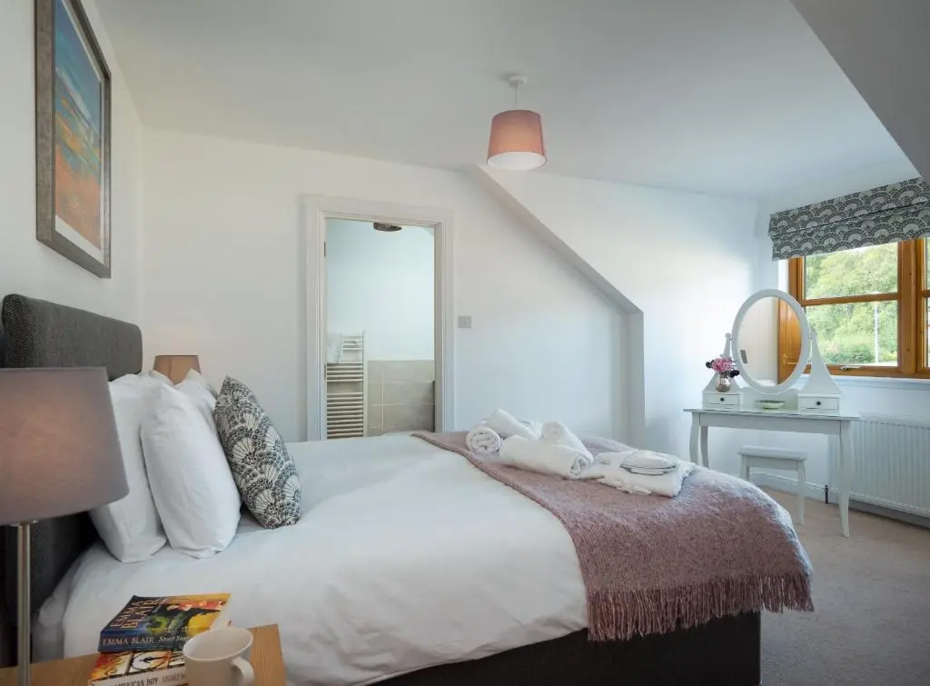 a bedroom with a large white bed and a mirror at Snowmass Lodge - hot tub in Aviemore in Aviemore