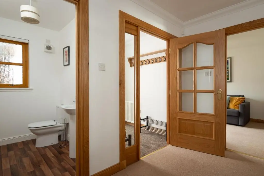 a bathroom with a toilet and a wooden door at Snowmass Lodge - hot tub in Aviemore in Aviemore