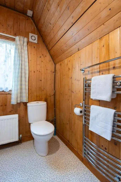 a bathroom with a toilet in a wooden wall at Chalet Rowan Cottage by Interhome in Inverness