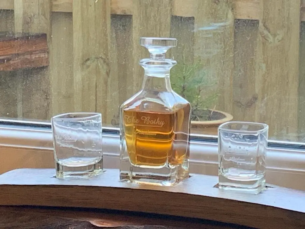 a bottle of whiskey and two glasses on a table at The Bothy Aberlour in Aberlour