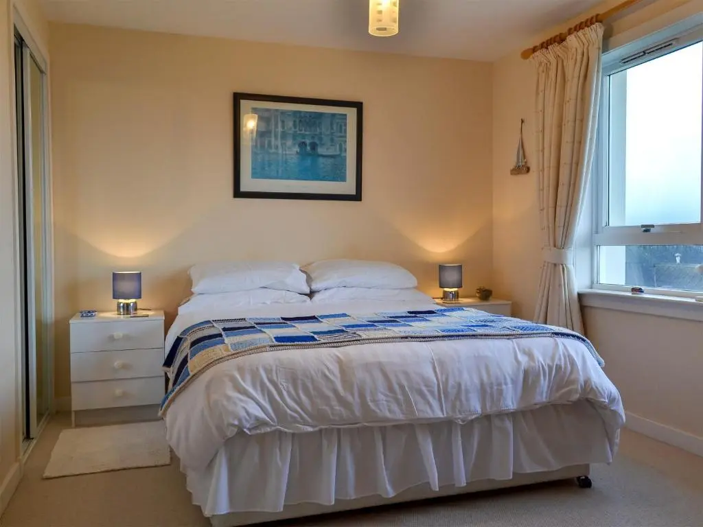 a bedroom with a bed with white sheets and a window at Brae Lodge in Cullen