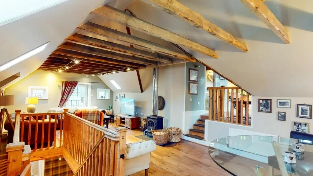 a living room with wooden beams ceilings and a glass table at The Maltings - lodge with hot tub in Nethy Bridge