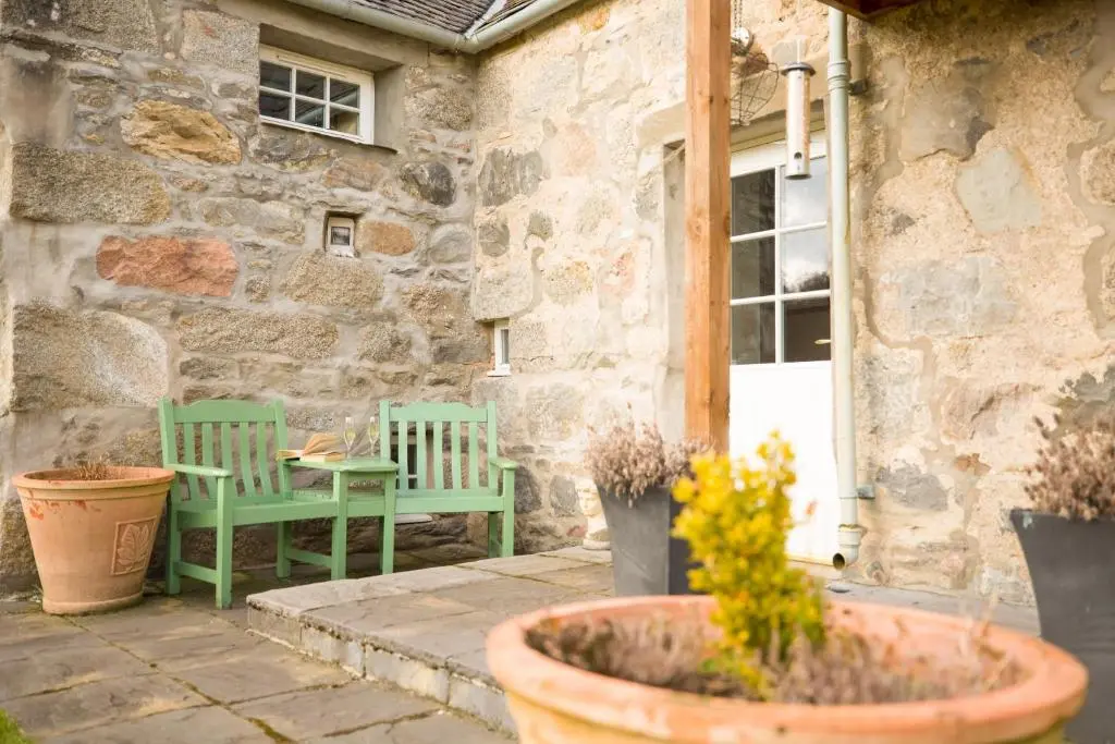 a patio with two green chairs and a table at The Maltings - lodge with hot tub in Nethy Bridge