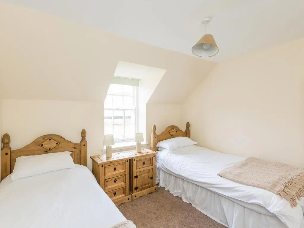 two twin beds in a room with a window at Balnain 1 in Cononbridge