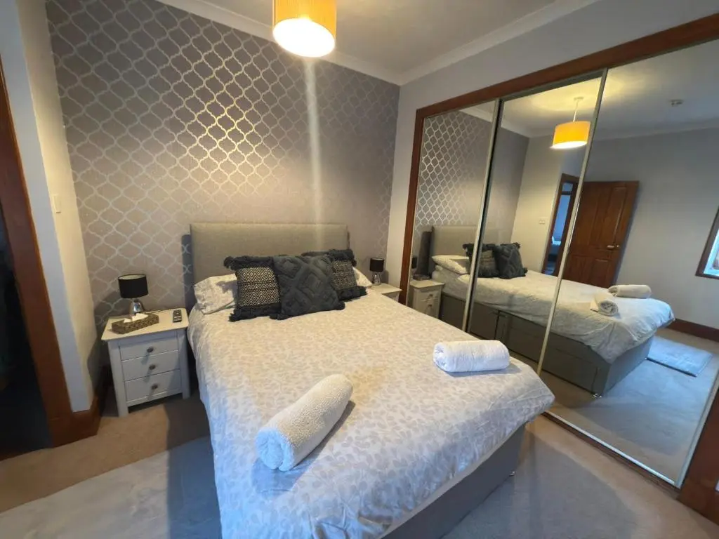 a bedroom with two beds and a large mirror at Newly Refurbished 2 Bedroom flat on NC500 route in Wick