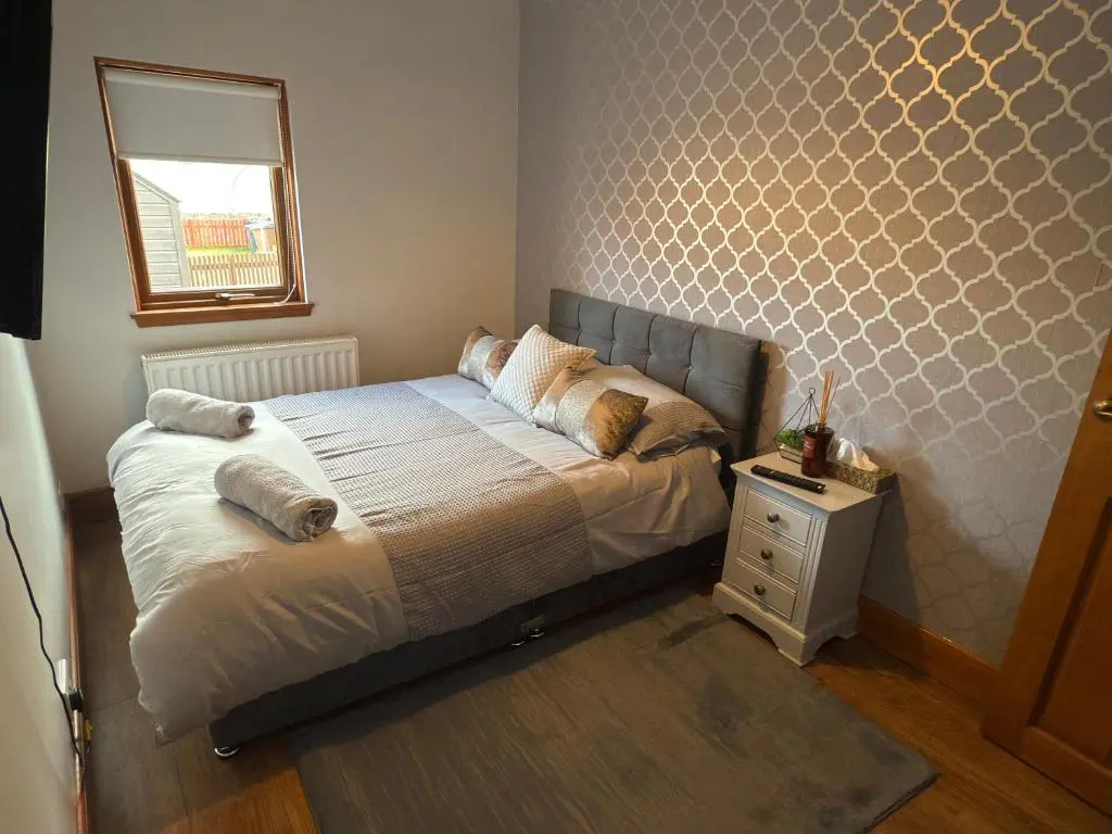 a bedroom with a bed with pillows and a window at Newly Refurbished 2 Bedroom flat on NC500 route in Wick