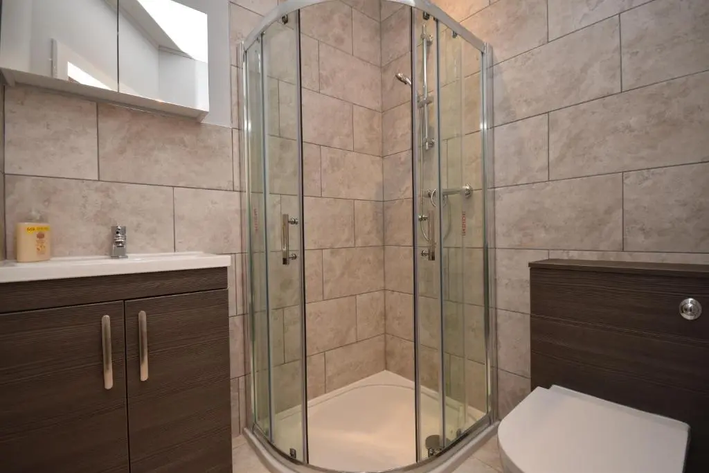 a bathroom with a shower with a toilet and a sink at Signature Apartments in Fraserburgh