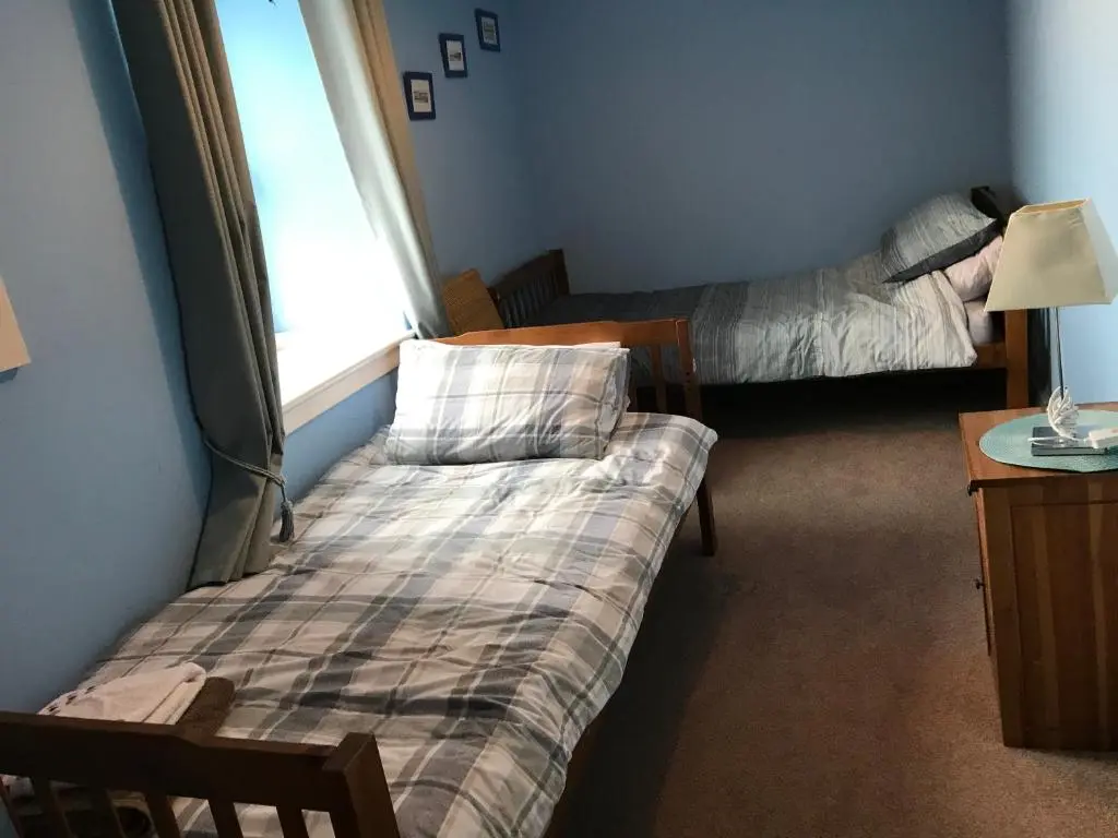 a room with two beds and a table and a window at PetFriendly-Beachfront-SunsetFacingSunPorch-Garden in Portmahomack