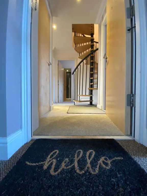 a hallway with a carpet with the word acid written on it at The Duplex Nairn- Spacious 3 Bedroom with sunny balcony in Nairn