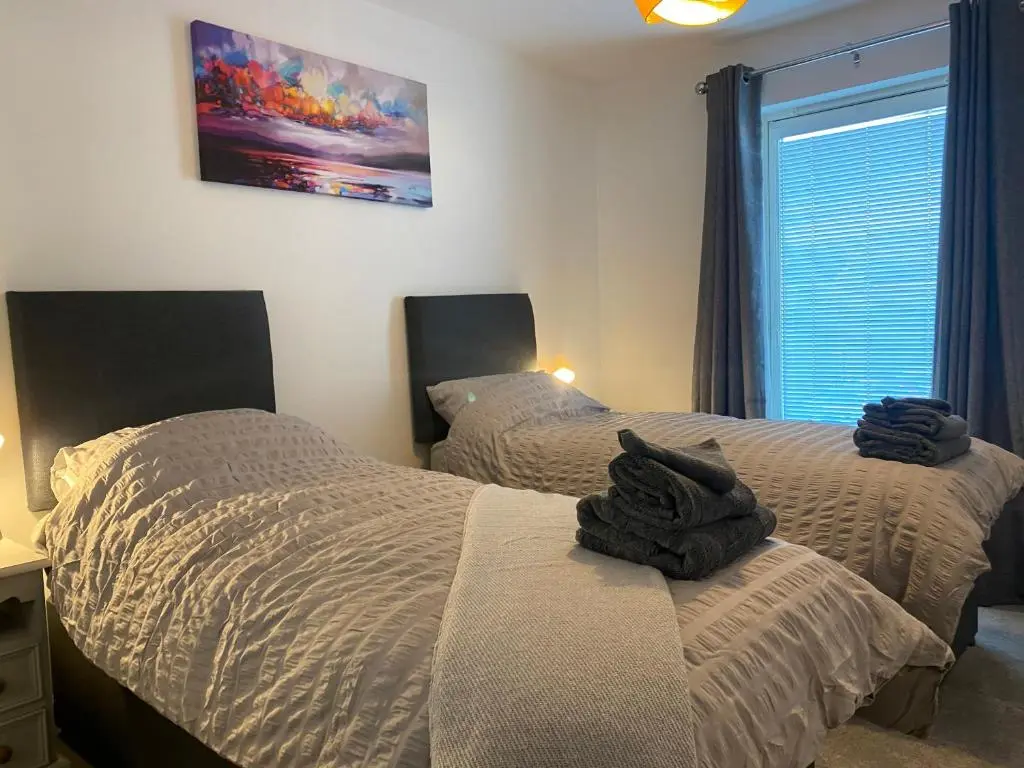 a bedroom with two twin beds and a window at The Duplex Nairn- Spacious 3 Bedroom with sunny balcony in Nairn