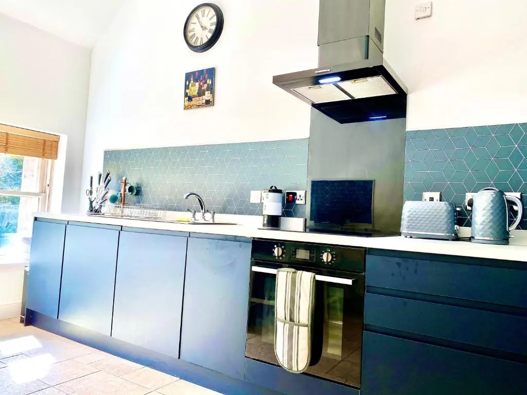 a kitchen with blue cabinets and a clock on the wall at Serviced Accommodation Moray - Lesmurdie House in Elgin