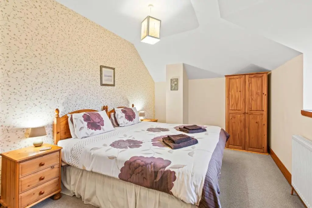a bedroom with a large bed and a wooden dresser at Freuchies Mill - A Holiday Home For All Seasons. in Blairgowrie
