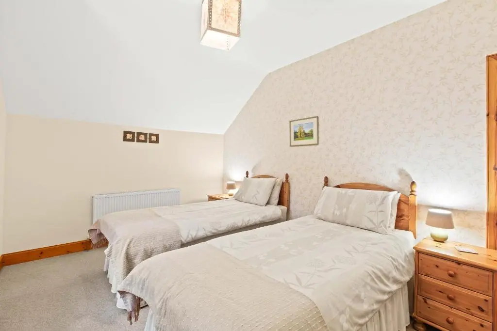 a bedroom with two beds and a dresser at Freuchies Mill - A Holiday Home For All Seasons. in Blairgowrie