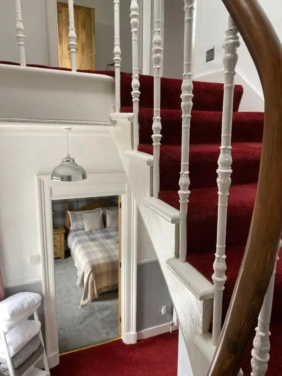 a bedroom with a bed and a staircase with a mirror at NC500, Wick Caithness Holiday Home in Wick