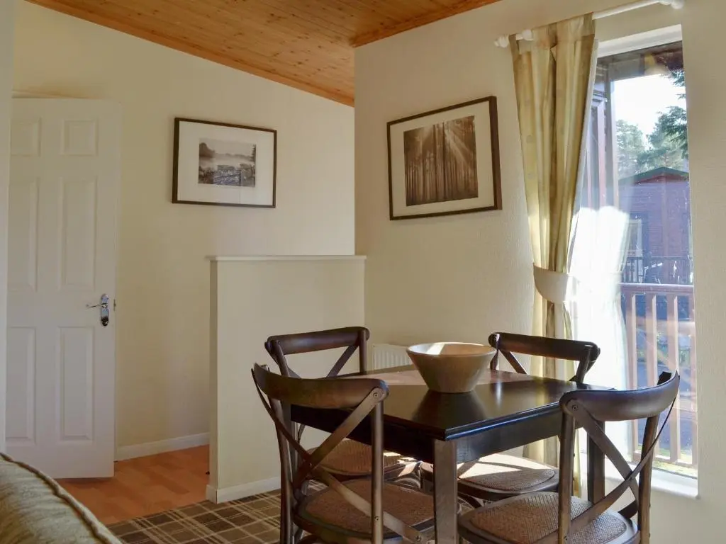a dining room with a table and chairs and a window at Lodge C- Uk33089 in Dinnet