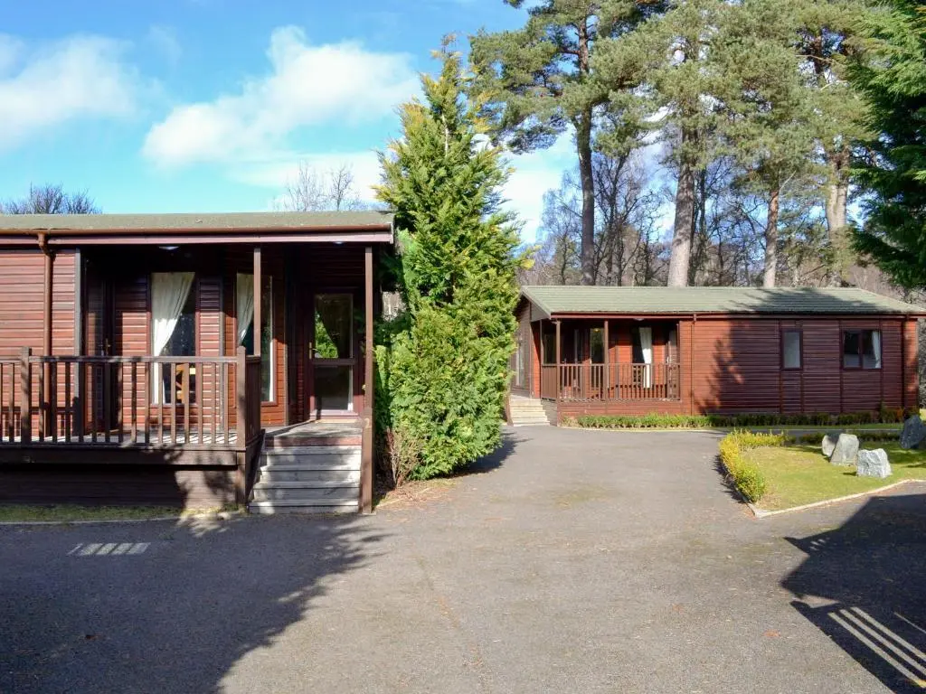 a small house with a porch and a tree at Lodge A- Uk33088 in Dinnet