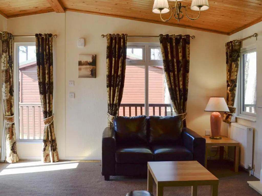 a living room with a leather couch and windows at Lodge F- Uk33092 in Dinnet