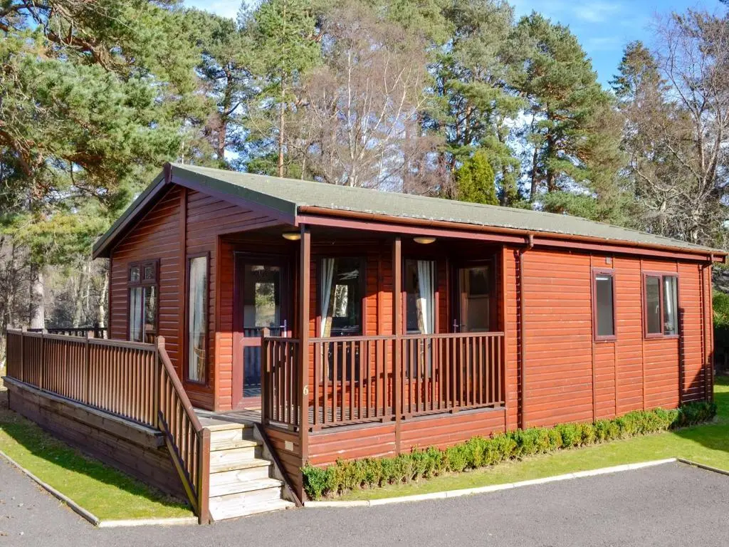 a wooden cabin with a porch and a balcony at Lodge F- Uk33092 in Dinnet