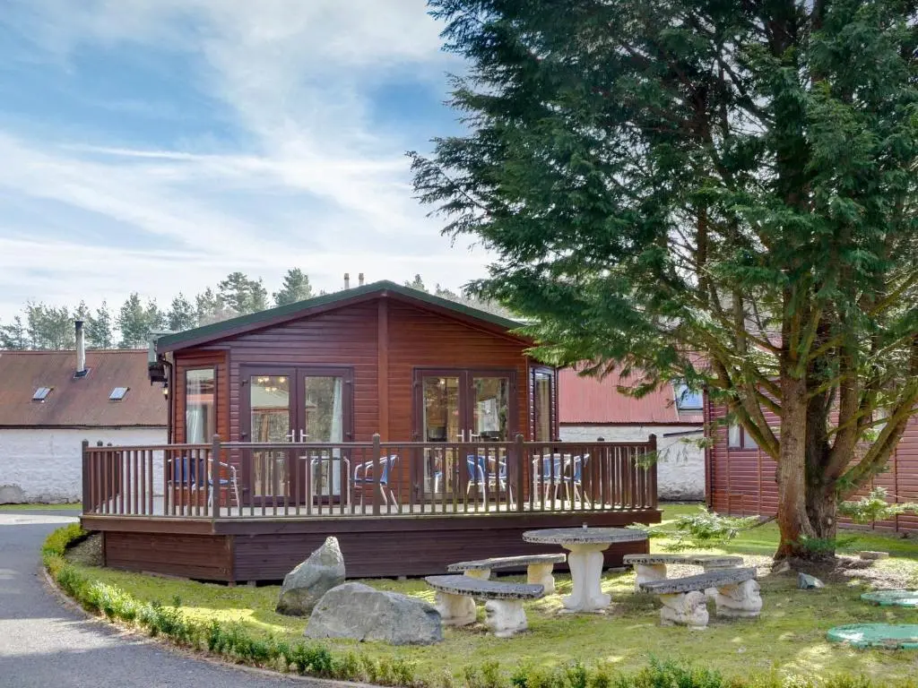 a small cabin with a deck and a picnic table at Lodge E- Uk33091 in Dinnet